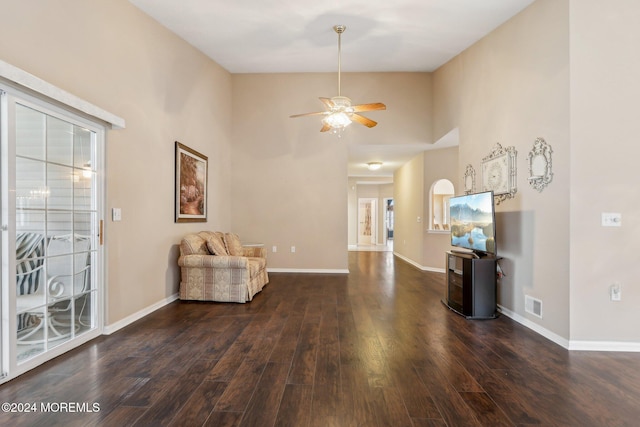 sitting room with ceiling fan, a towering ceiling, and dark hardwood / wood-style floors