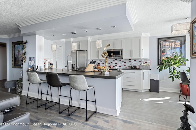 kitchen with kitchen peninsula, pendant lighting, stainless steel appliances, and white cabinetry