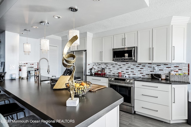 kitchen featuring hanging light fixtures, decorative backsplash, a textured ceiling, white cabinetry, and stainless steel appliances