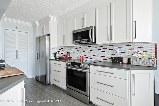 kitchen featuring backsplash, a textured ceiling, stainless steel appliances, crown molding, and white cabinetry