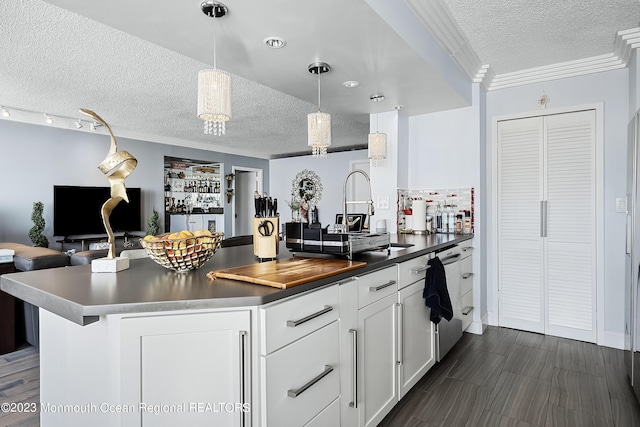 kitchen with white cabinets, pendant lighting, a textured ceiling, and crown molding