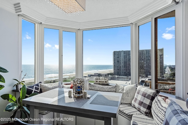 sunroom / solarium featuring a wealth of natural light, a water view, and a view of the beach