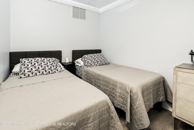 bedroom featuring wood-type flooring, a textured ceiling, and ornamental molding