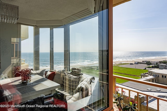 sunroom / solarium with a water view and a beach view