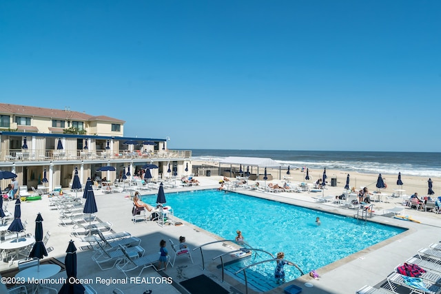 view of pool with a water view and a view of the beach