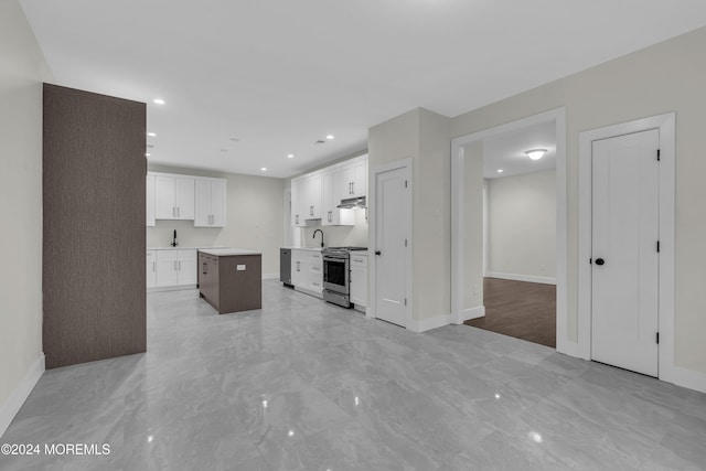 kitchen with white cabinetry, stainless steel gas stove, a kitchen island, and sink