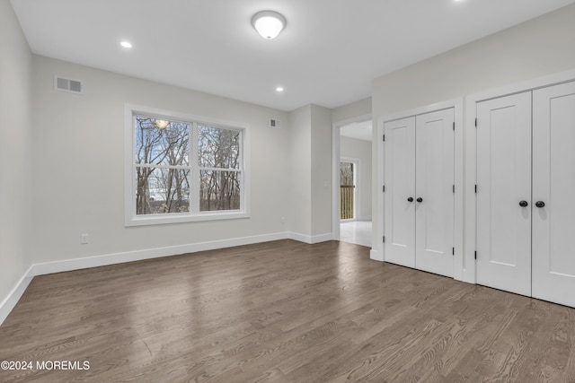 unfurnished bedroom with multiple closets and wood-type flooring