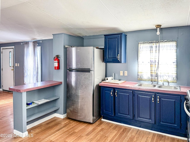 8 Monique Cir, Hazlet, NJ 07730 - kitchen featuring light wood-style floors, a sink, freestanding refrigerator, and blue cabinetry