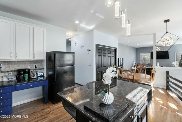 kitchen with a center island, tasteful backsplash, dark stone countertops, black refrigerator, and white cabinets