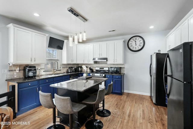 kitchen with a center island, black fridge, blue cabinets, sink, and white cabinetry