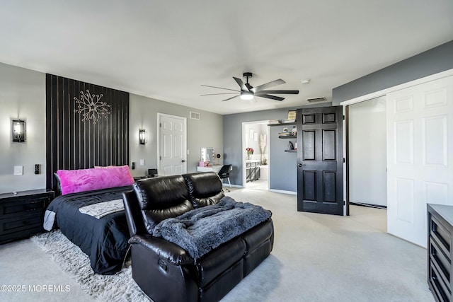 bedroom with ceiling fan, light colored carpet, and connected bathroom