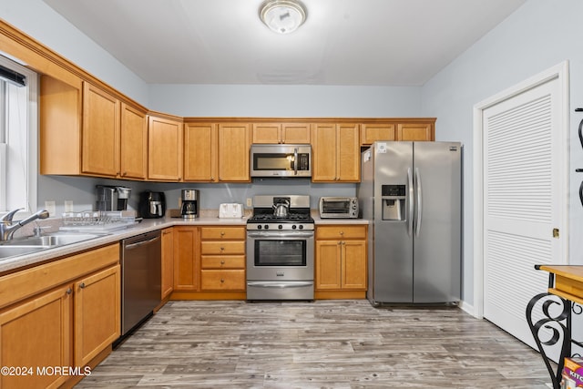 kitchen with sink, stainless steel appliances, and light hardwood / wood-style flooring