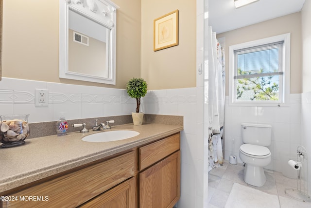 bathroom featuring vanity, toilet, and tile walls