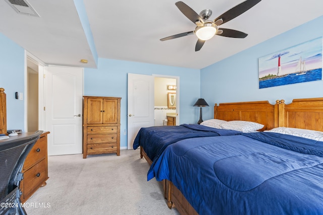 bedroom with ceiling fan, light carpet, and connected bathroom