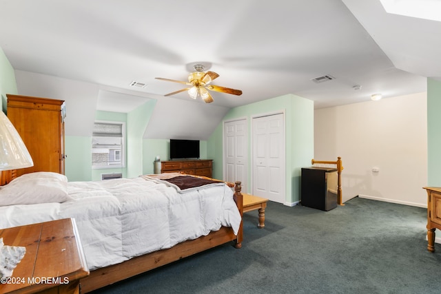 bedroom with two closets, dark carpet, ceiling fan, and lofted ceiling