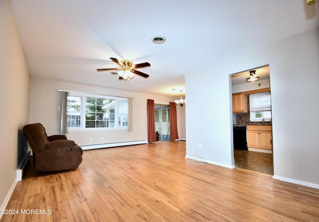 unfurnished room featuring ceiling fan with notable chandelier, light hardwood / wood-style floors, and baseboard heating