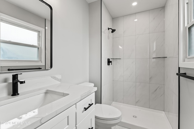 bathroom with tiled shower, vanity, and toilet