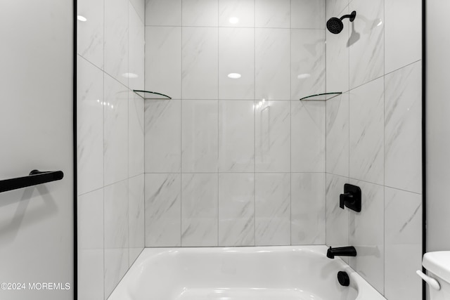 bathroom featuring toilet and tiled shower / bath