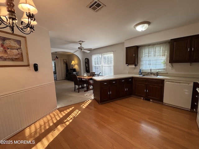 kitchen featuring white dishwasher, ceiling fan with notable chandelier, sink, light wood-type flooring, and kitchen peninsula