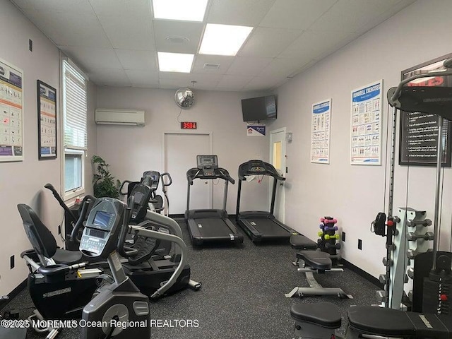 gym with a drop ceiling and a wall unit AC