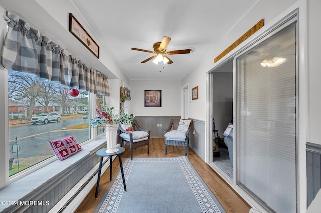 interior space featuring wood-type flooring, ceiling fan, and a baseboard heating unit