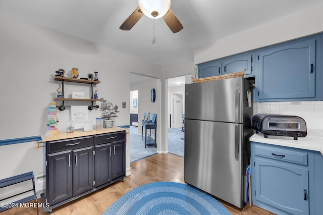 kitchen featuring backsplash, stainless steel refrigerator, ceiling fan, and blue cabinets