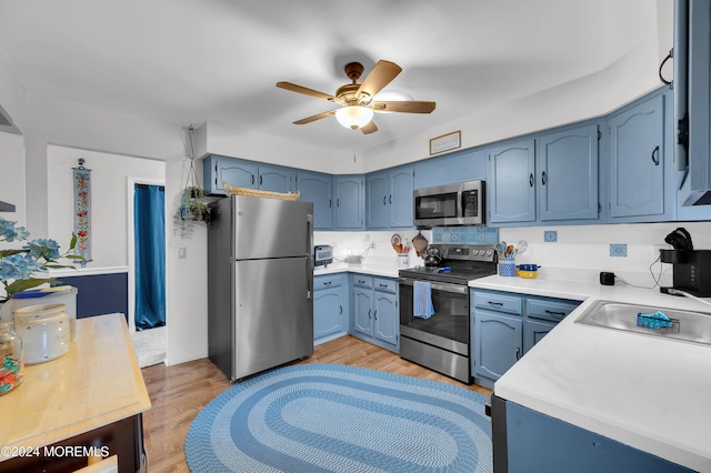 kitchen featuring blue cabinetry, ceiling fan, stainless steel appliances, and light hardwood / wood-style floors