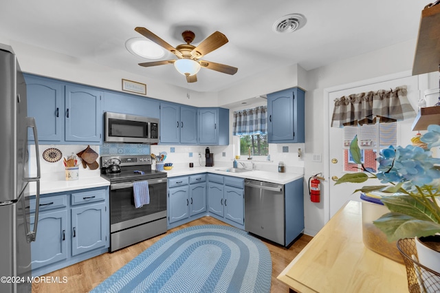 kitchen featuring sink, ceiling fan, blue cabinetry, appliances with stainless steel finishes, and light hardwood / wood-style floors