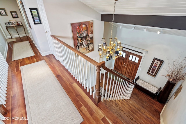 stairs featuring hardwood / wood-style floors, wooden ceiling, lofted ceiling, and an inviting chandelier