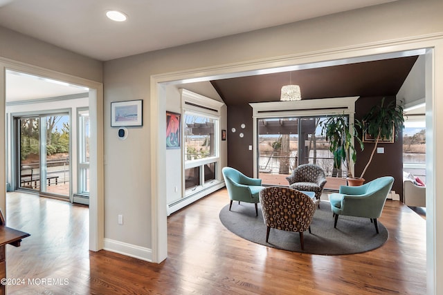 interior space with hardwood / wood-style floors, lofted ceiling, and a baseboard heating unit