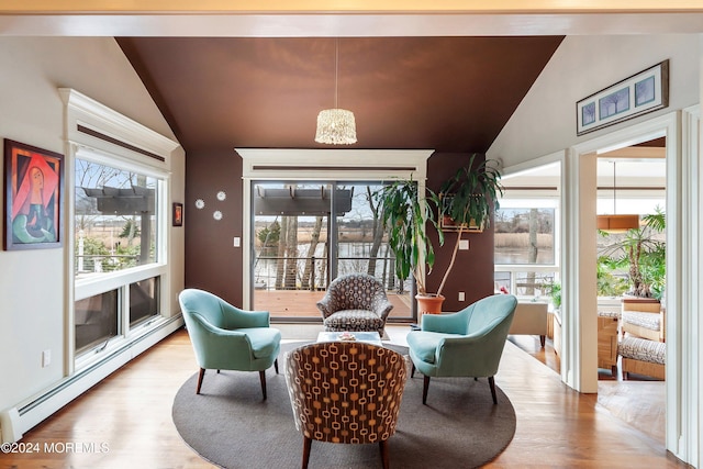 living area featuring plenty of natural light, vaulted ceiling, and a baseboard heating unit