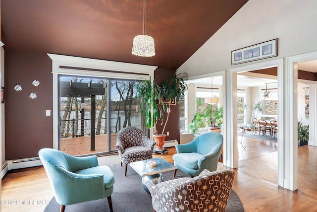 interior space featuring high vaulted ceiling, light hardwood / wood-style flooring, and a baseboard heating unit