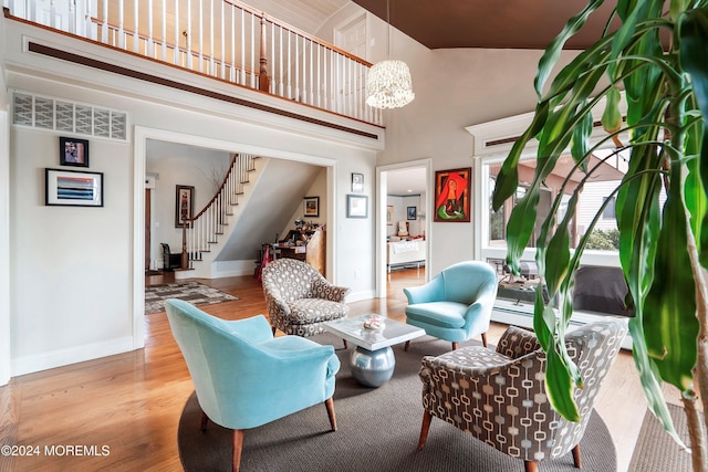 living room with light hardwood / wood-style floors, high vaulted ceiling, and a notable chandelier