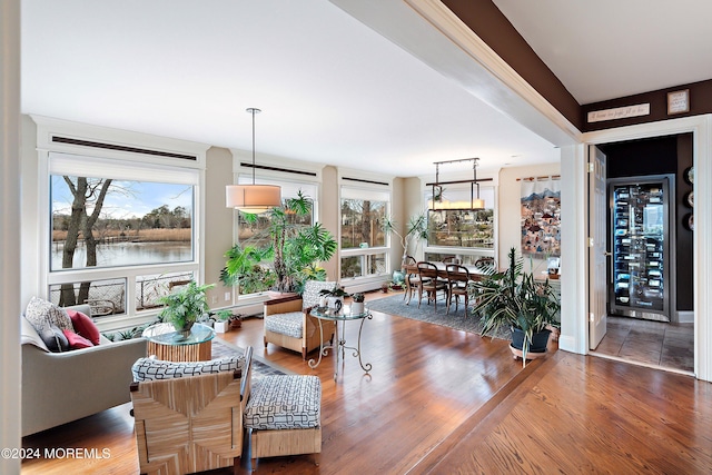 living room with wine cooler, hardwood / wood-style floors, and a water view