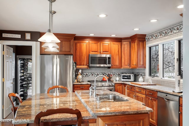 kitchen featuring decorative light fixtures, a kitchen breakfast bar, a kitchen island with sink, and appliances with stainless steel finishes