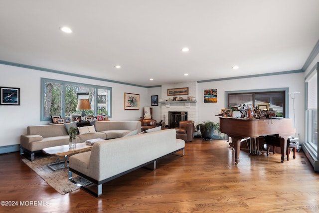 living room with wood-type flooring, a brick fireplace, and ornamental molding