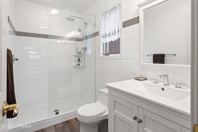 bathroom with hardwood / wood-style floors, toilet, tile walls, tasteful backsplash, and a tile shower