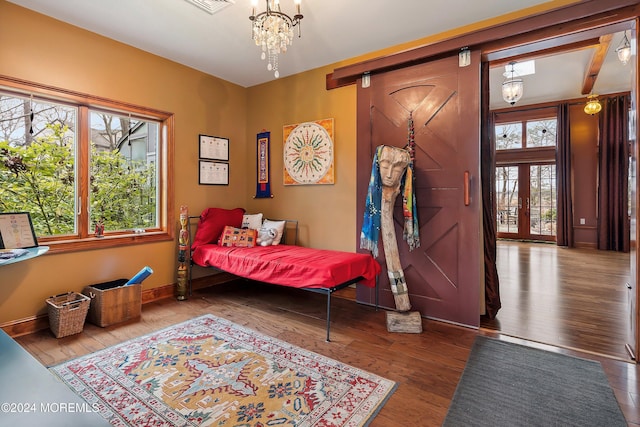 bedroom with hardwood / wood-style floors, beamed ceiling, a chandelier, and french doors