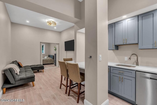 kitchen with gray cabinets, sink, stainless steel dishwasher, and light hardwood / wood-style floors