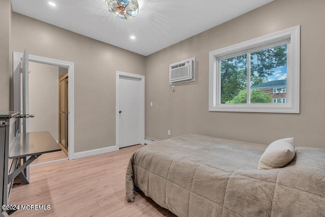 bedroom featuring a wall mounted AC, a baseboard radiator, and light wood-type flooring