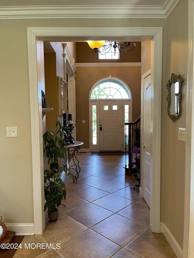 tiled entryway featuring ornamental molding and an inviting chandelier