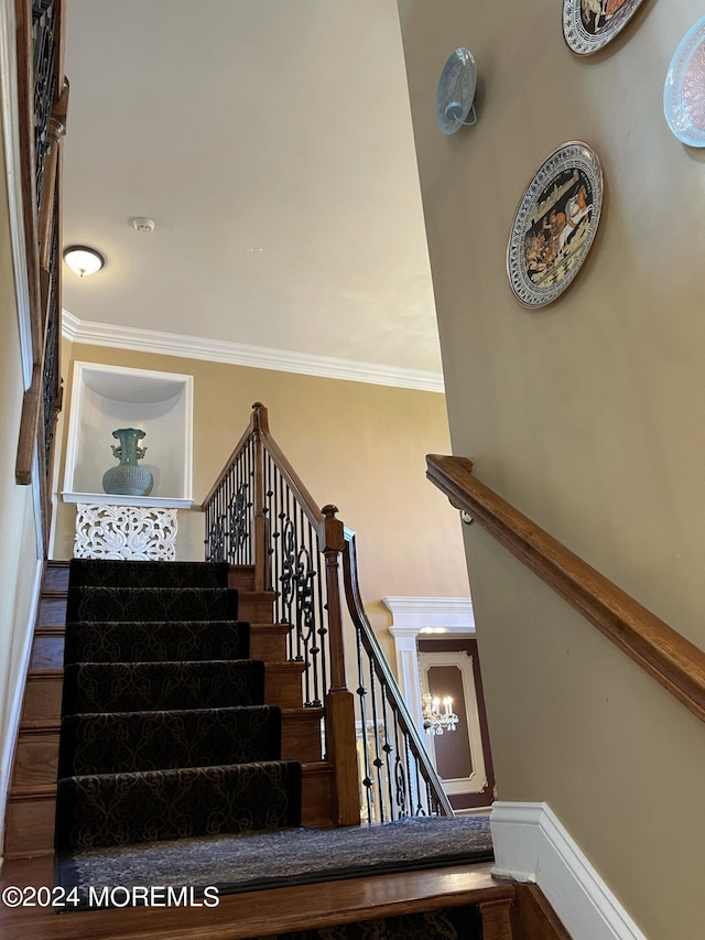 stairs with crown molding and a notable chandelier