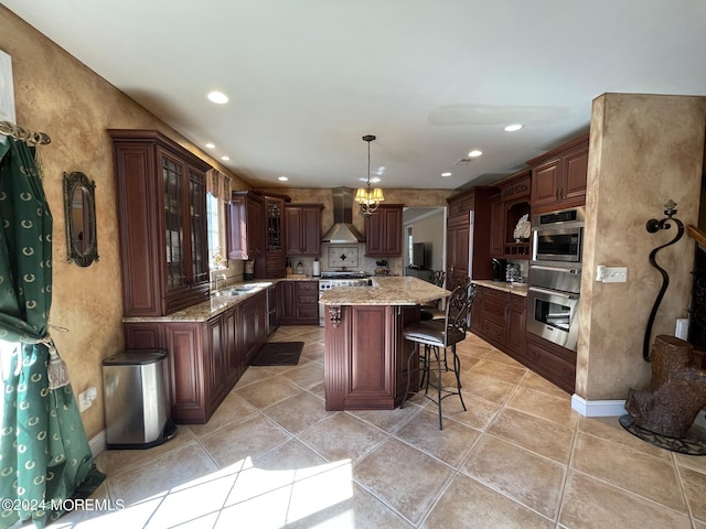 kitchen with pendant lighting, a center island, an inviting chandelier, wall chimney range hood, and dark brown cabinetry