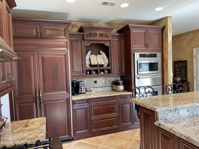 kitchen with oven, light tile patterned flooring, light stone counters, and backsplash