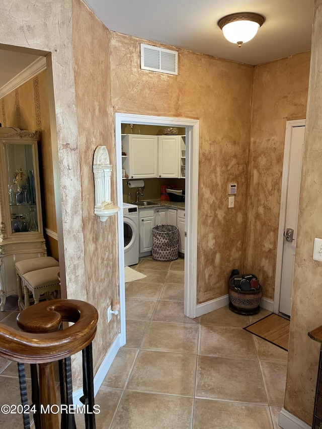 bathroom with tile patterned flooring, crown molding, washer / dryer, and sink