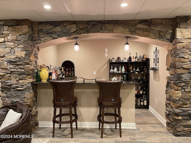 bar featuring decorative light fixtures and hardwood / wood-style flooring