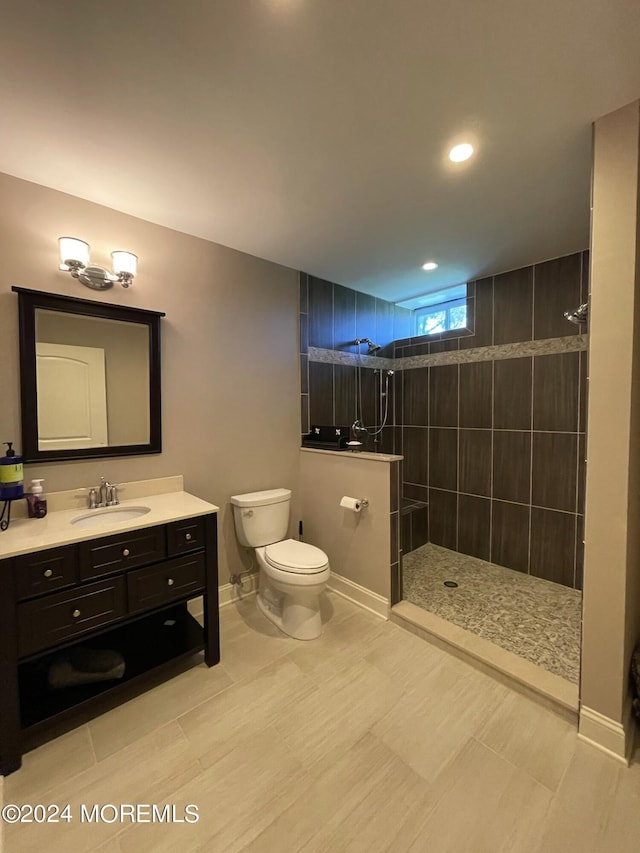 bathroom featuring vanity, toilet, and a tile shower