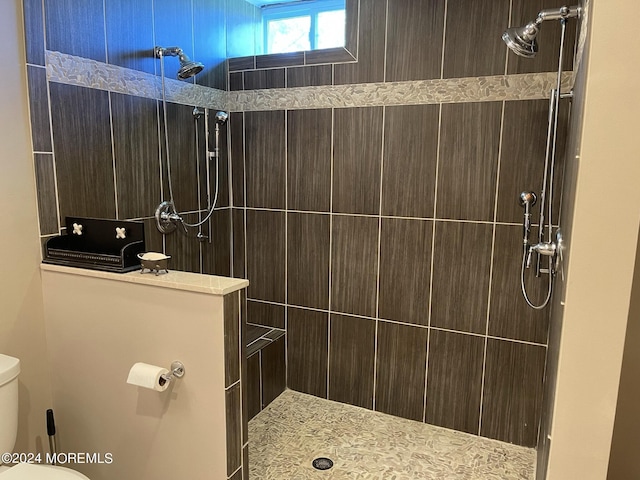 bathroom featuring a tile shower and toilet