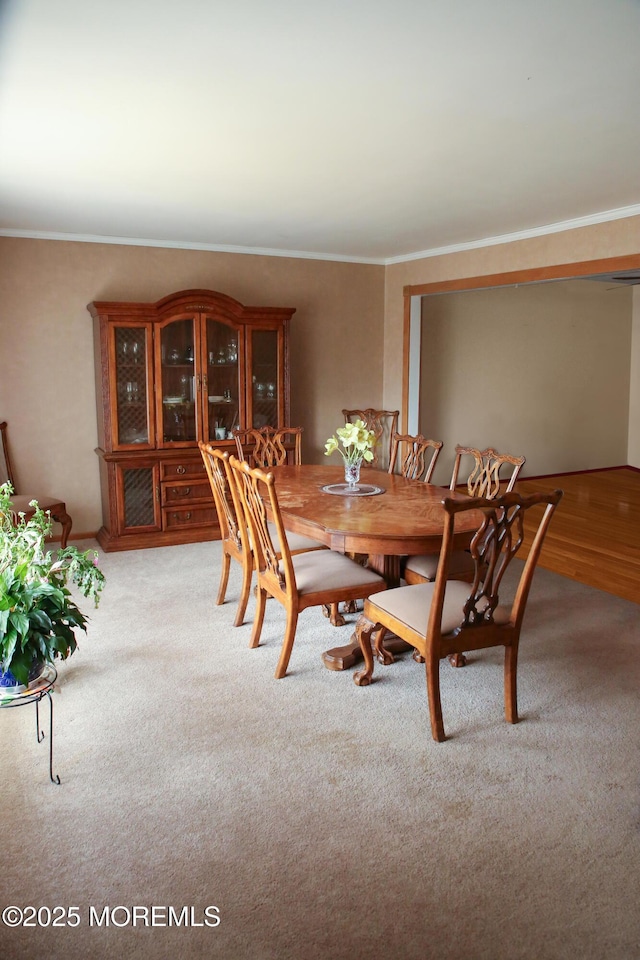 dining space featuring light colored carpet and ornamental molding