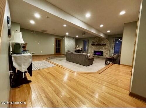 living room with light hardwood / wood-style floors and a stone fireplace